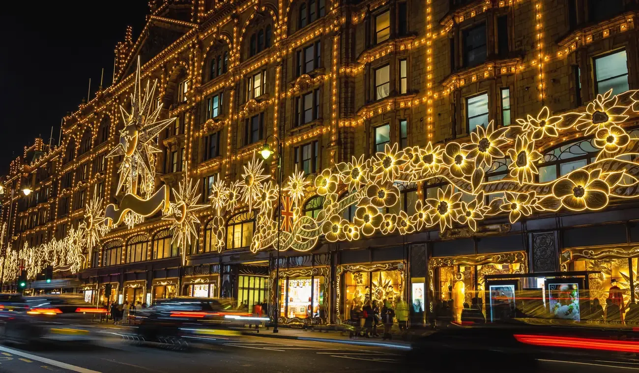 The facade of Harrods on Brompton Road in Knightsbridge covered in golden Christmas lights at night