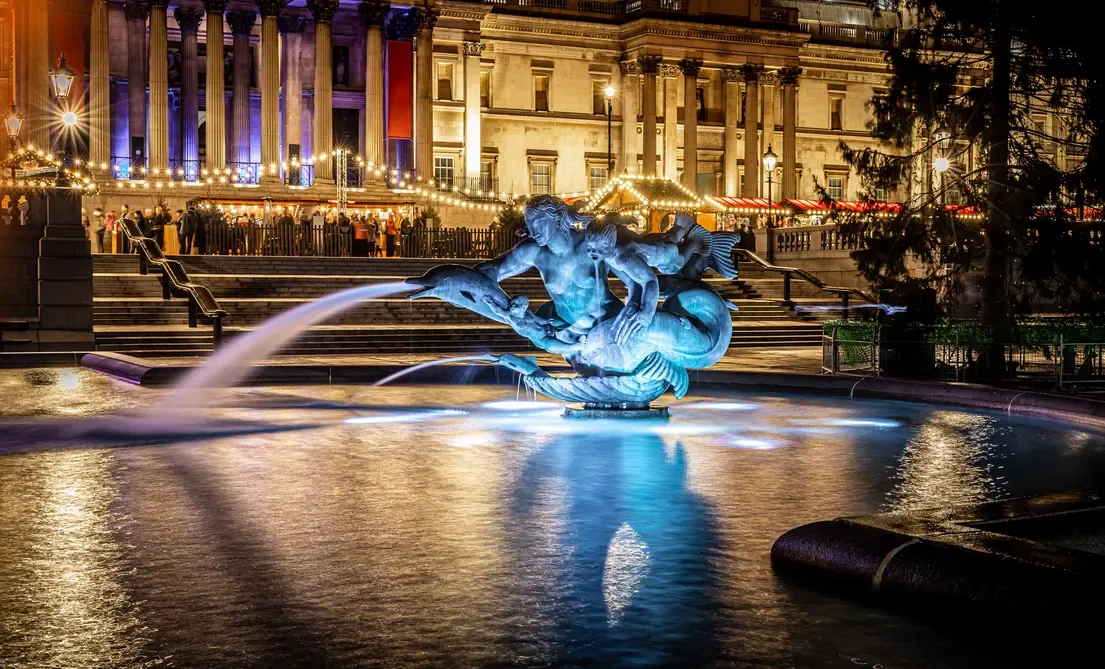 Fountains of Trafalgar Square illuminated at night in London