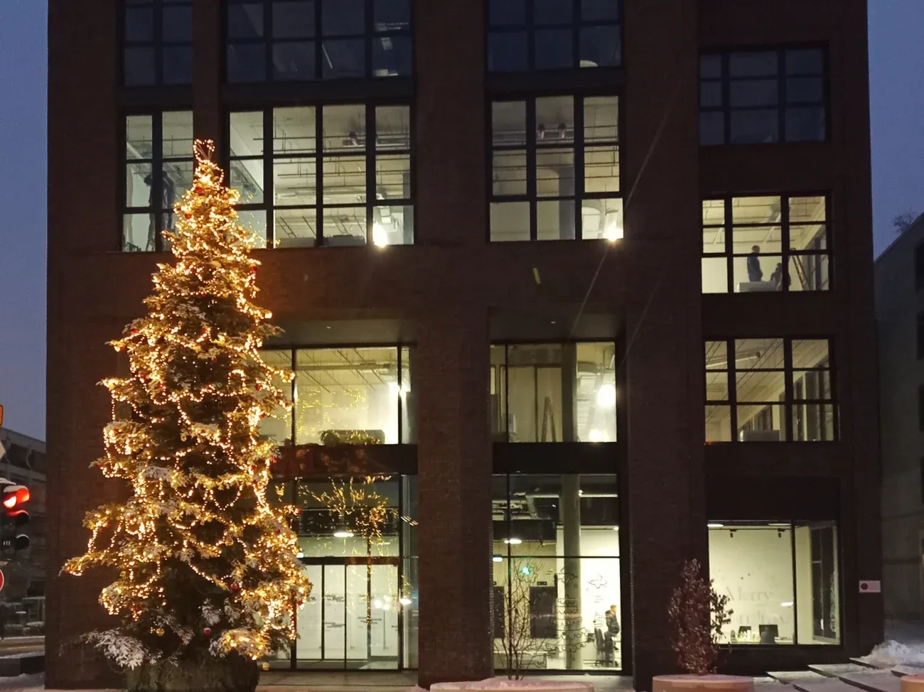 A lit Christmas tree in front of a building of Die Macherei in Berg am Laim, Munich