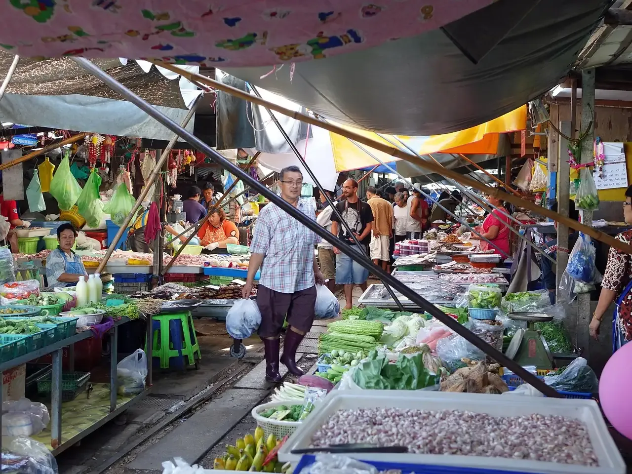 Produce stalls beside the track at Maeklong railway market, Samut Songkhram