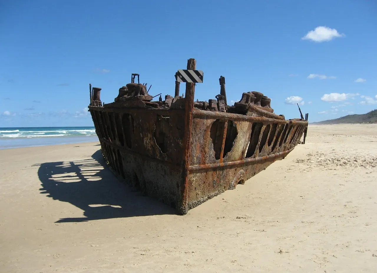 The rusting hull of the Maheno shipwreck on the ocean beach at K'gari
