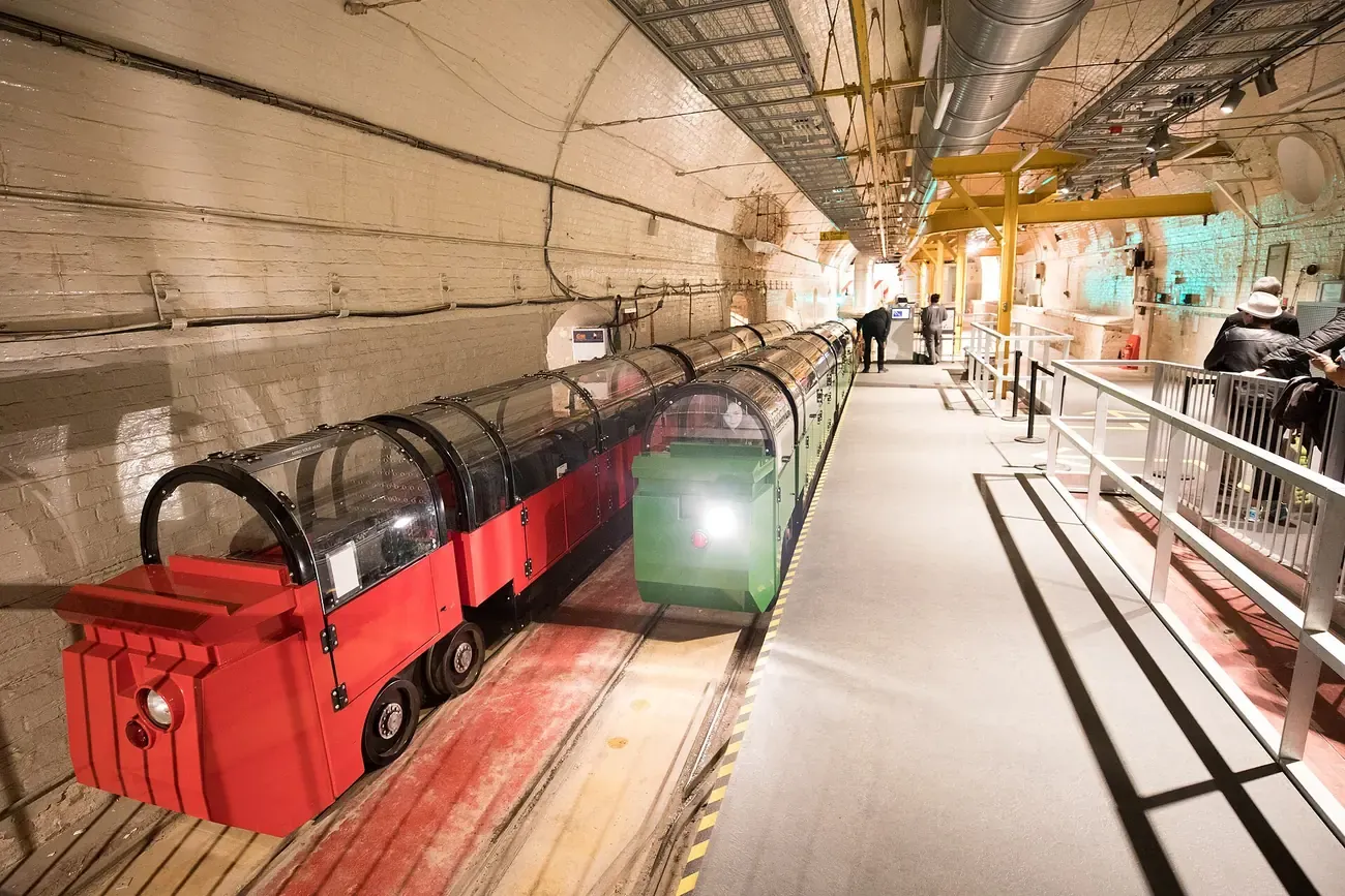 Red and green Mail Rail visitor trains waiting in the underground tunnel at the Postal Museum in London