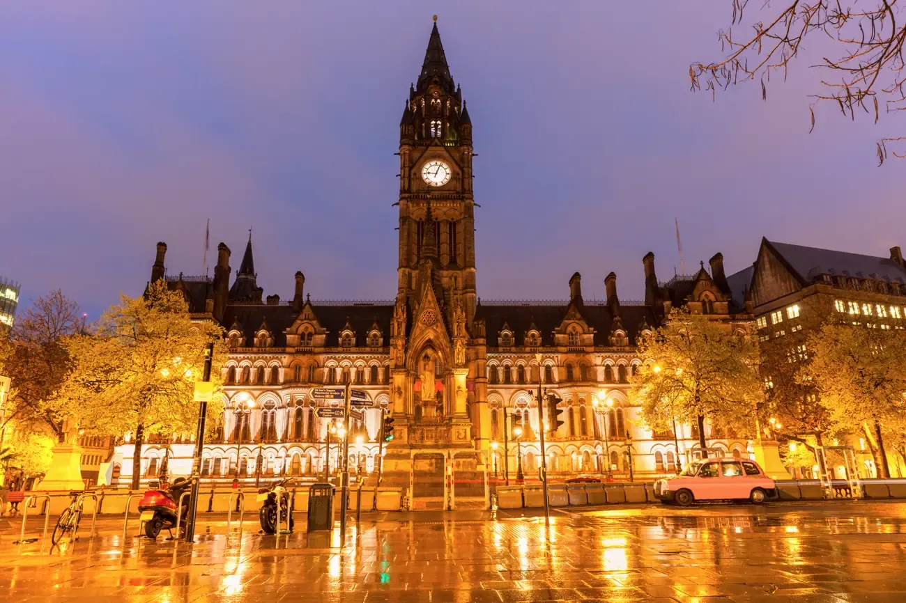 Manchester Town Hall and Albert Square illuminated at dusk in the rain