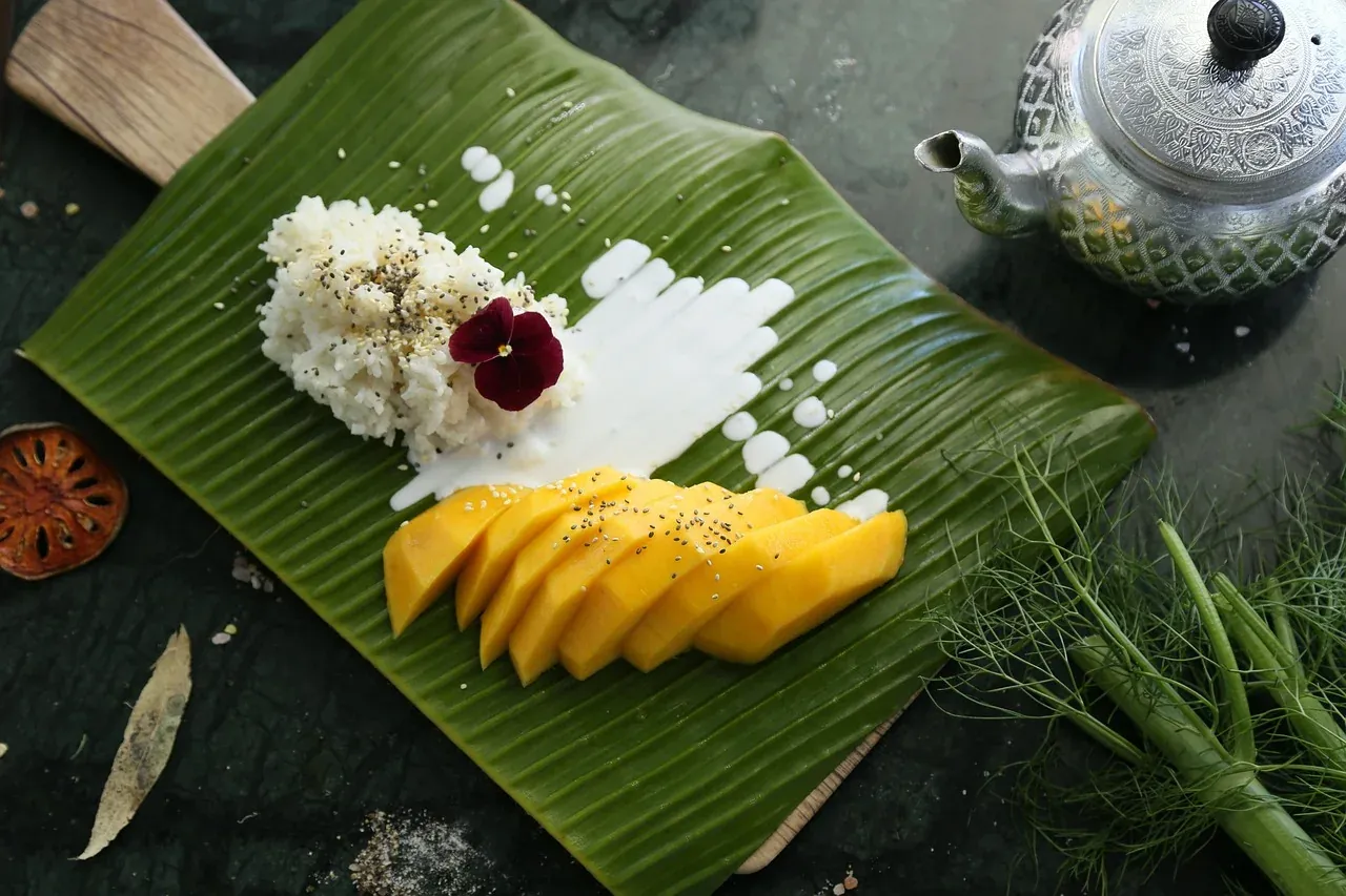 Sliced mango with sticky rice and coconut milk on a banana leaf