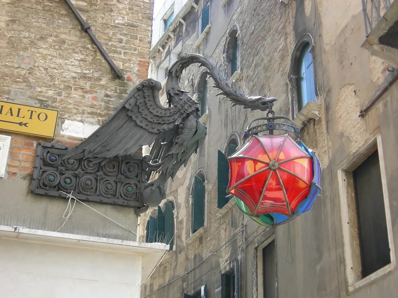 The wrought-iron dragon holding the coloured umbrella lantern of the Marforio sign in the Mercerie, Venice