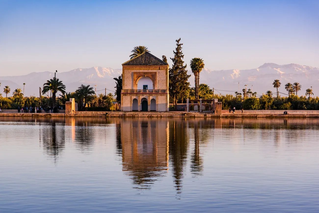 The Menara Gardens pavilion reflected in its basin with the snow-capped Atlas Mountains behind, Marrakech