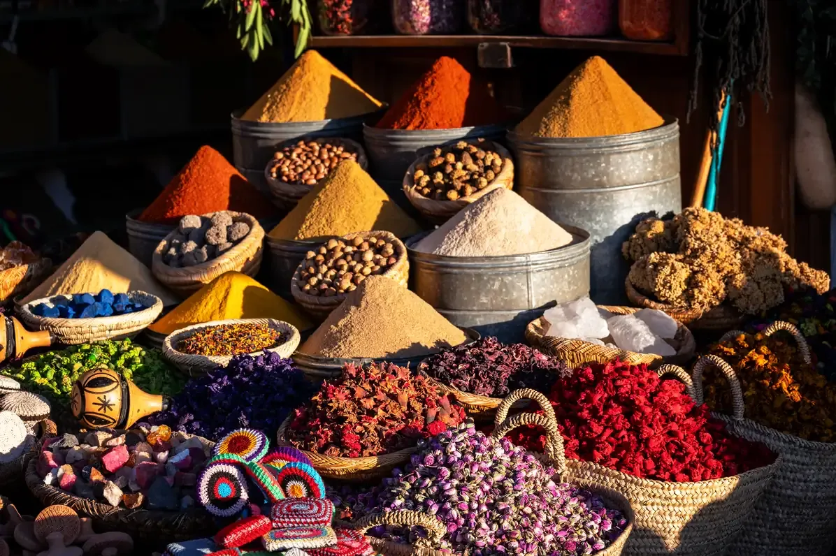 Cones of coloured spices and baskets of dried flowers on a market stall in Marrakech