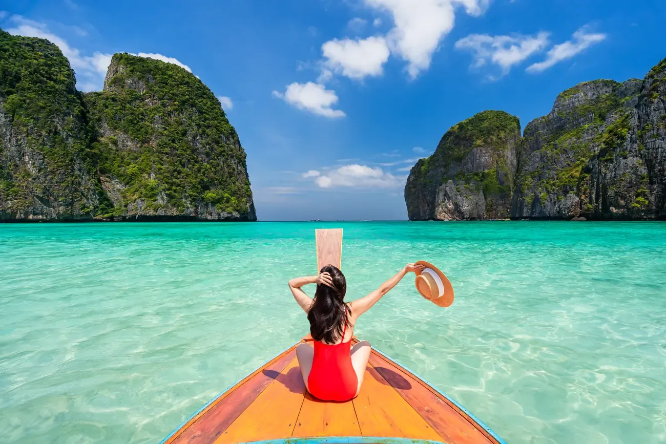 A traveller on a longtail boat at Maya Bay, Phi Phi Islands, Thailand