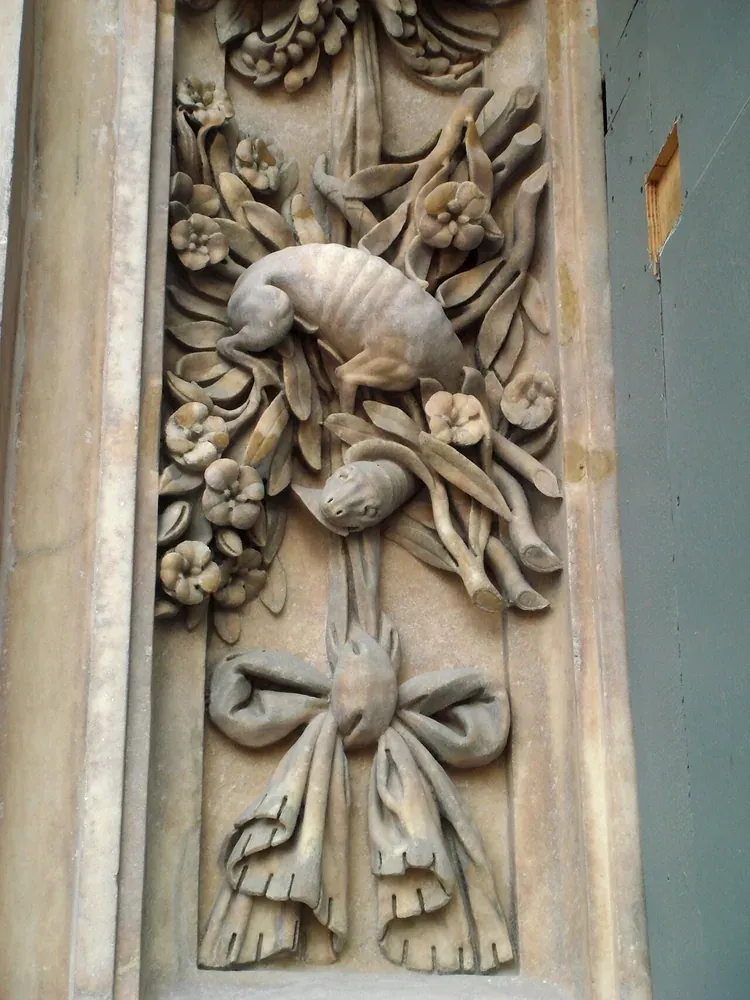 Marble relief beside the main portal of Milan Cathedral showing a dog-bodied creature with a long neck among flowers and foliage