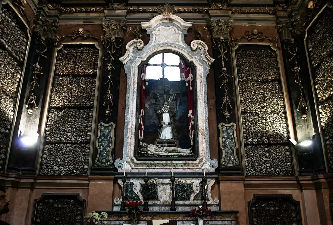 Altar of the ossuary chapel of San Bernardino alle Ossa in Milan, framed by walls lined with human skulls and bones