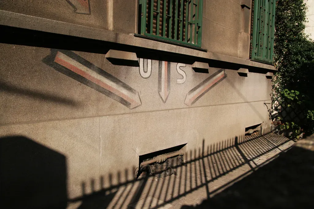 Wartime painted arrows and the letters U S marking an air-raid shelter emergency exit on a building wall in Milan