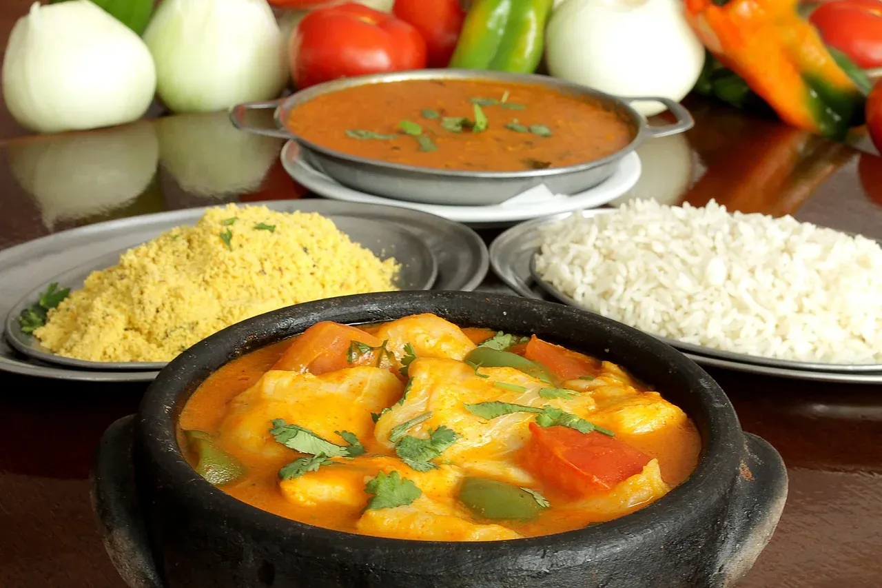 Moqueca seafood stew served in a clay pot with rice and side dishes