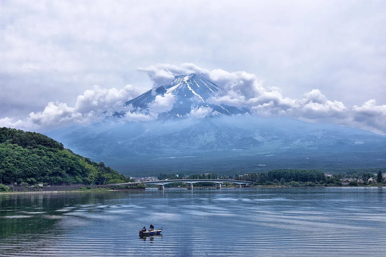 A small boat on Lake Kawaguchi below the clouded summit of Mount Fuji