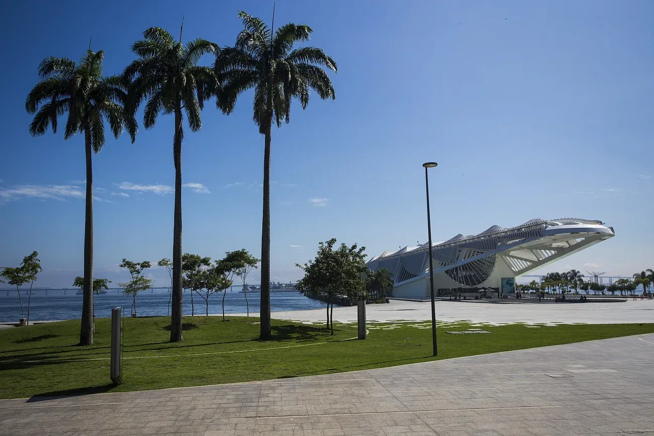 The white roof of the Museum of Tomorrow behind royal palms at Praca Maua