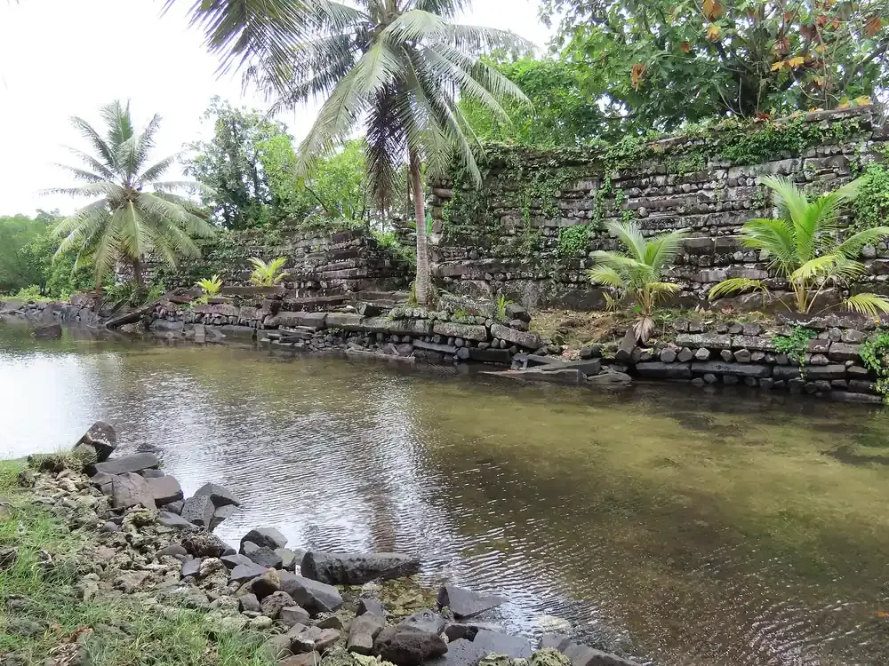 Basalt column walls of Nan Madol rising beside a tidal canal on Pohnpei, Micronesia