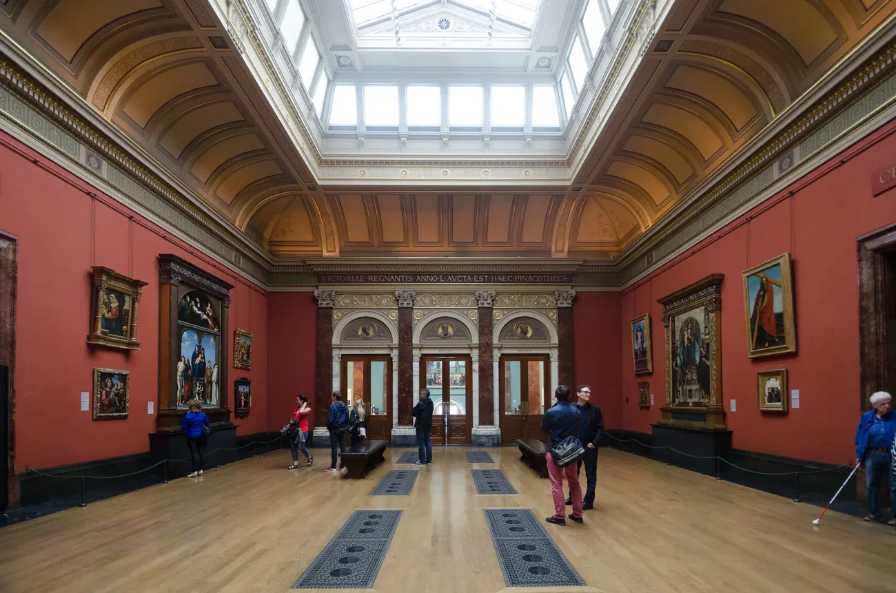 A red-walled picture room with skylit ceiling inside the National Gallery in London