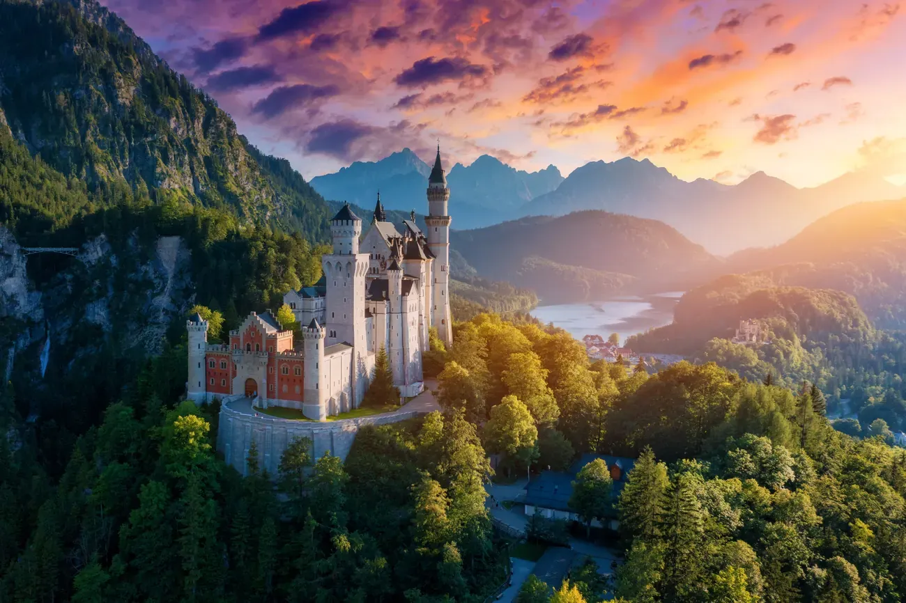 Aerial sunset view of Neuschwanstein Castle with a lake below