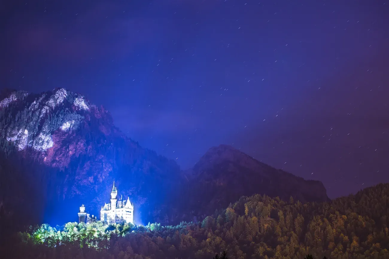 Neuschwanstein Castle illuminated at night under a starry sky