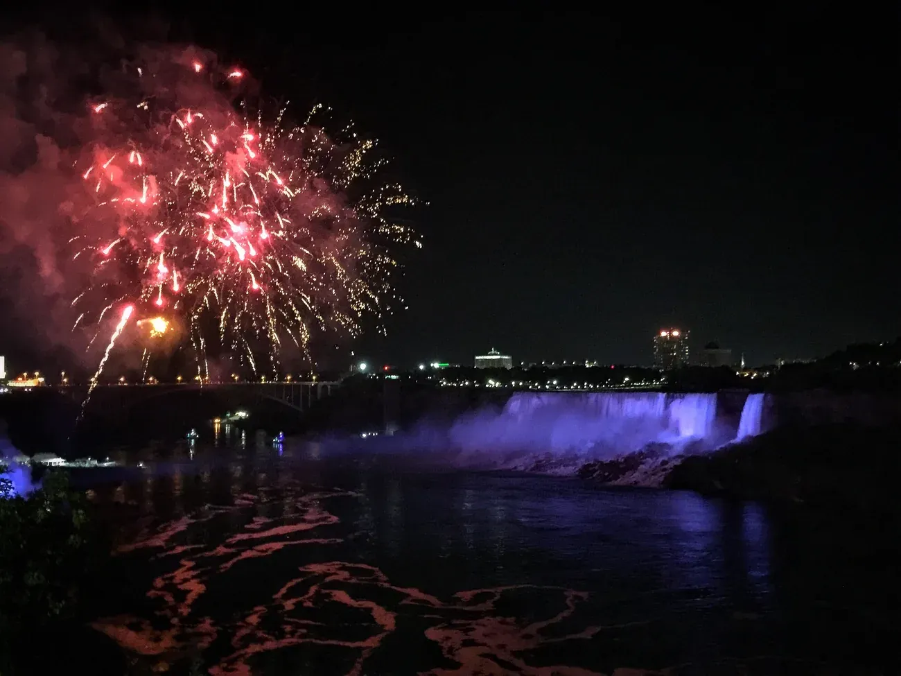 Fireworks display at night over Niagara Falls illuminated in blue