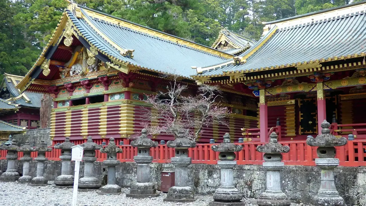A painted shrine hall and rows of stone lanterns at Nikko Toshogu