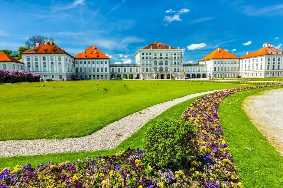 Nymphenburg Palace behind a lawn and a curved bed of pansies on the garden side in Munich