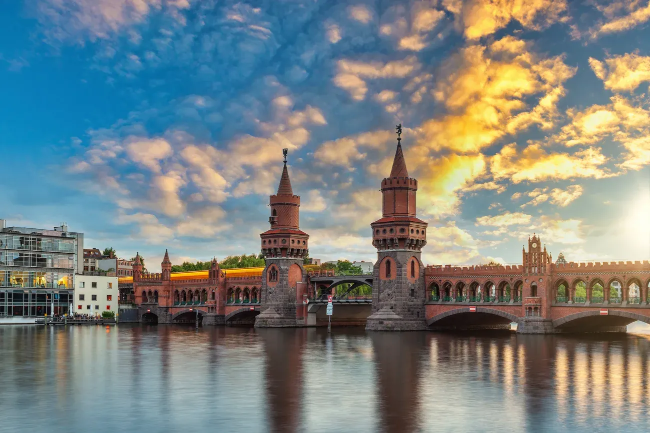 The twin brick towers of the Oberbaum Bridge over the Spree at sunrise in Berlin, with a U-Bahn train on the upper deck