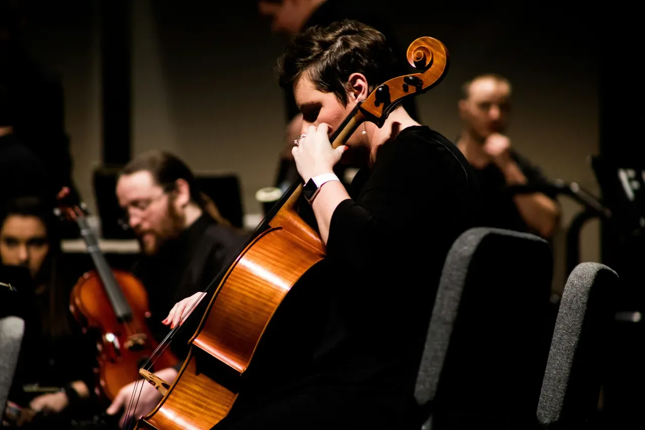 Side view of a musician playing the cello in an orchestra