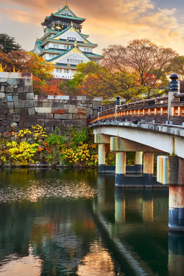 Osaka Castle above its moat and a bridge in autumn