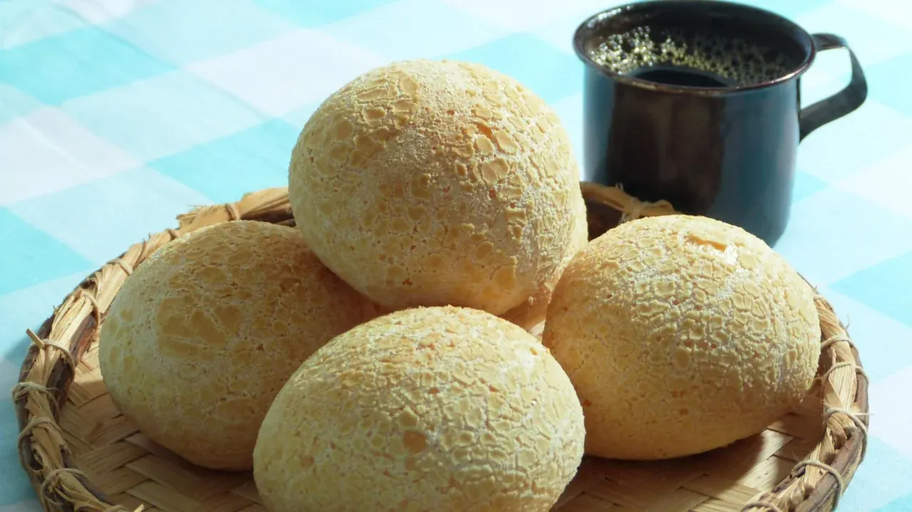 Warm pao de queijo cheese rolls in a basket beside a mug