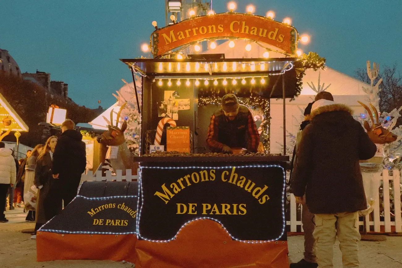 A roasted chestnut stall at a Christmas market in Paris at night