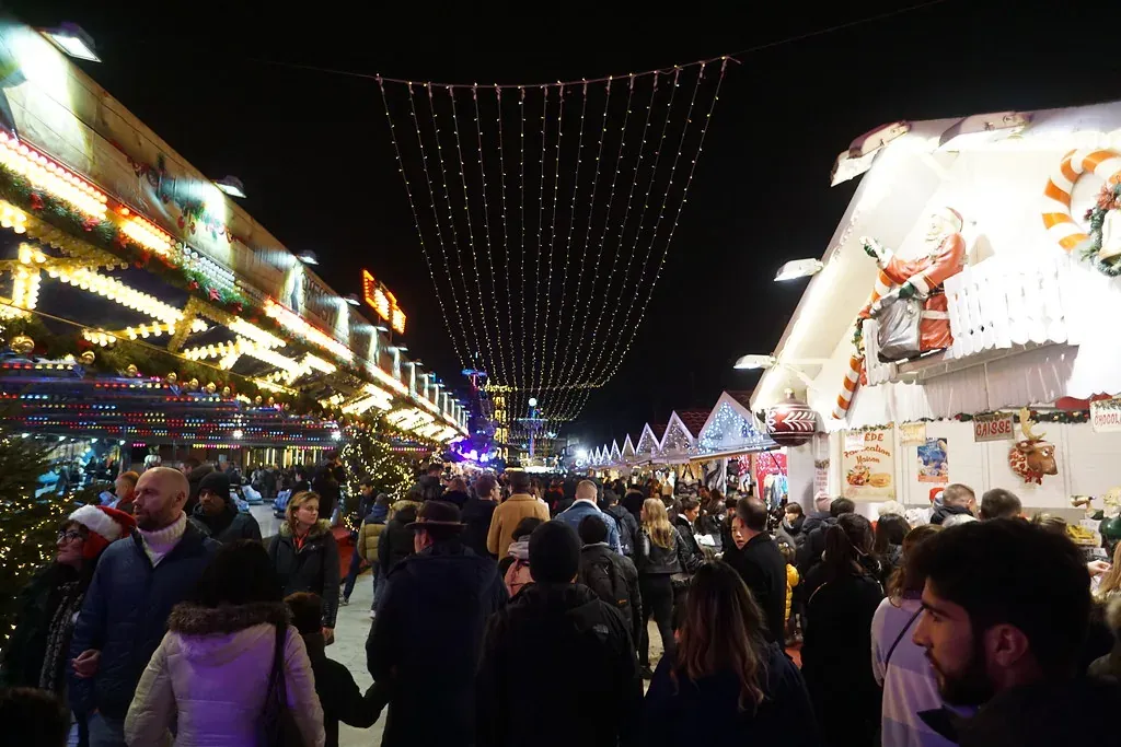 Visitors walking between the chalets of the Tuileries Christmas market in Paris at night