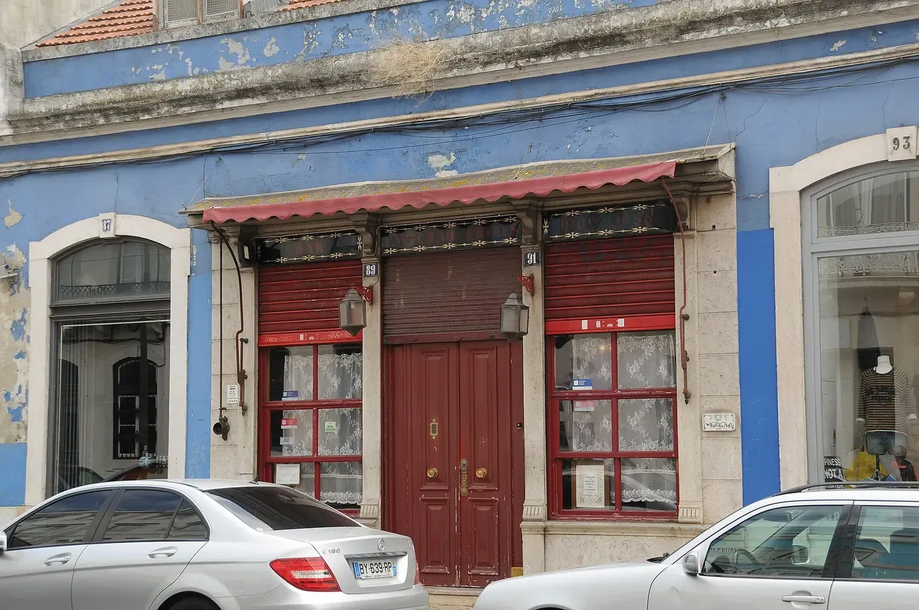 The corner facade and red door entrance of the Pavilhao Chines bar in Lisbon