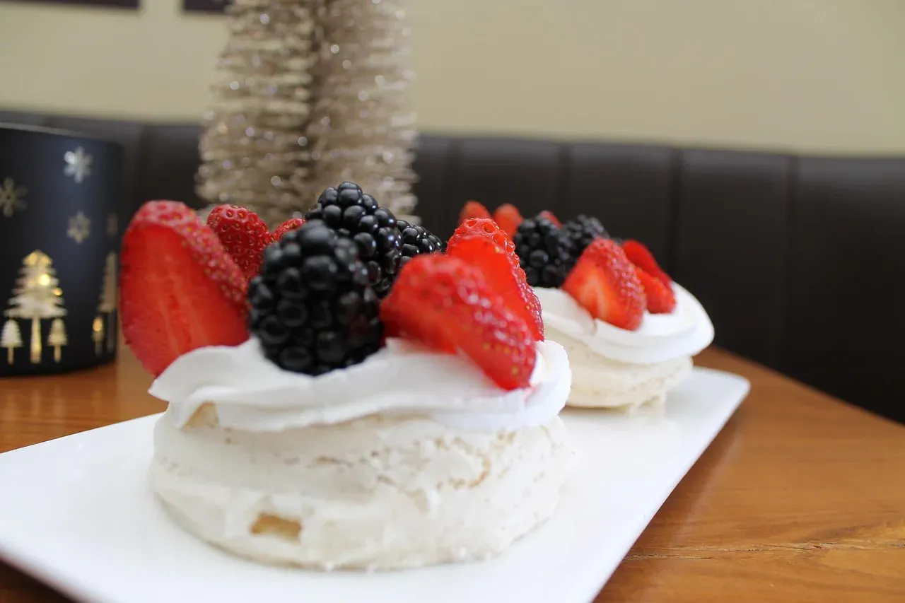 A pavlova topped with whipped cream and fresh berries