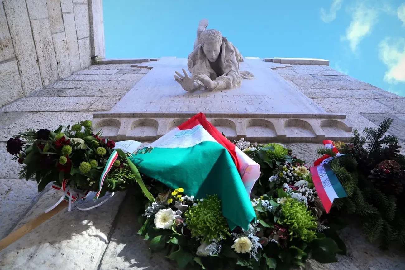 The Peter Mansfeld memorial relief of a falling young man, with wreaths and a Hungarian flag, in Buda, Budapest
