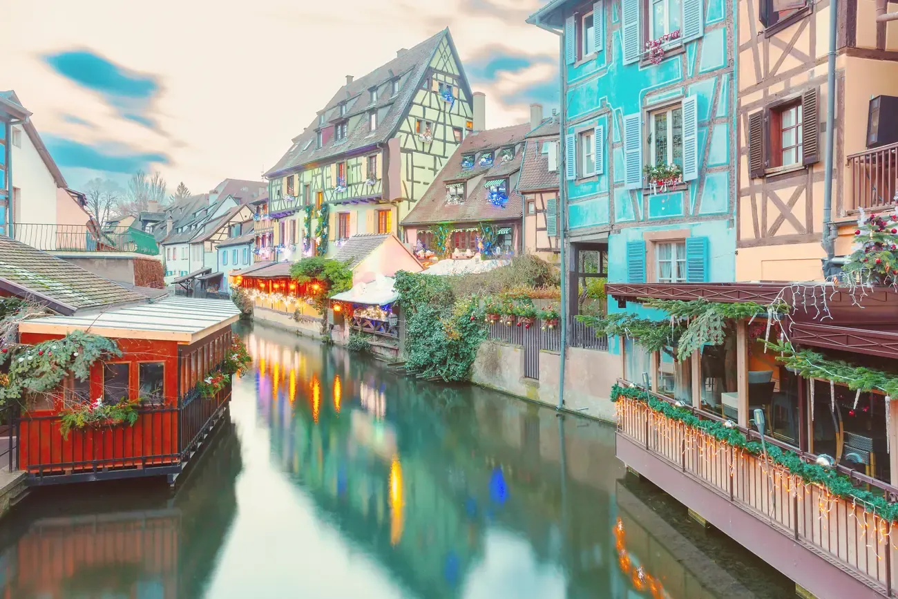 The Petite Venise canal in Colmar at Christmas, with decorated stalls and half-timbered houses along the water