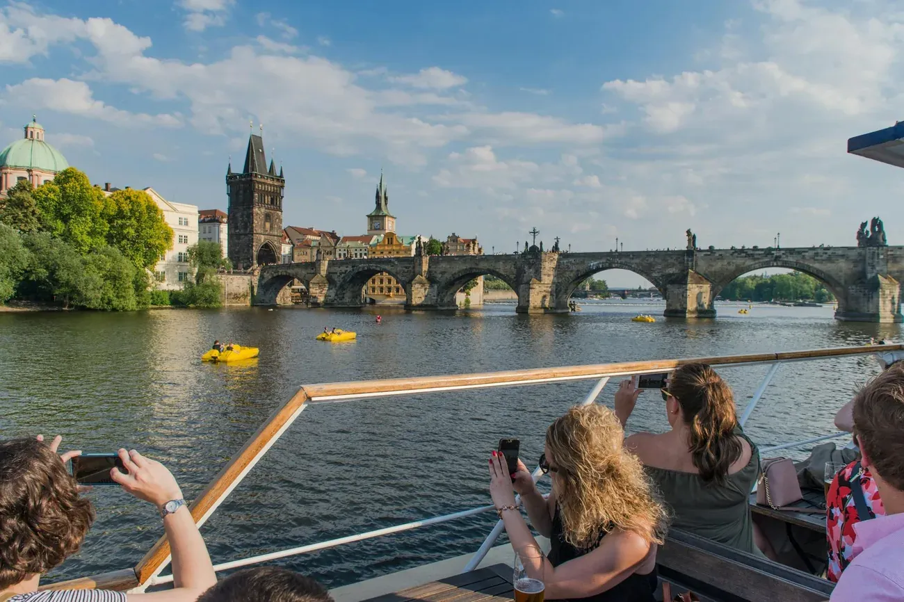 Passengers photographing Charles Bridge from a Vltava cruise boat