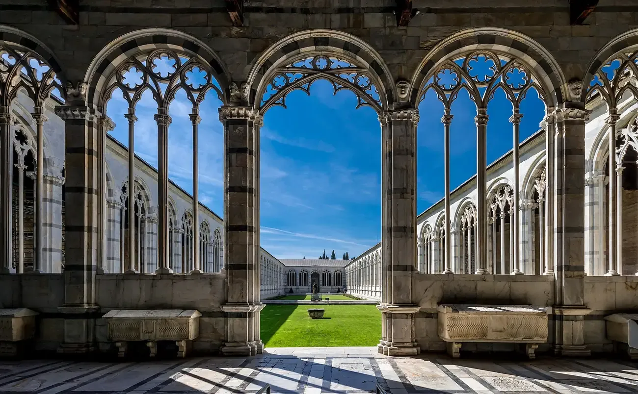 Gothic marble arcades framing the lawn of the Camposanto cloister in Pisa