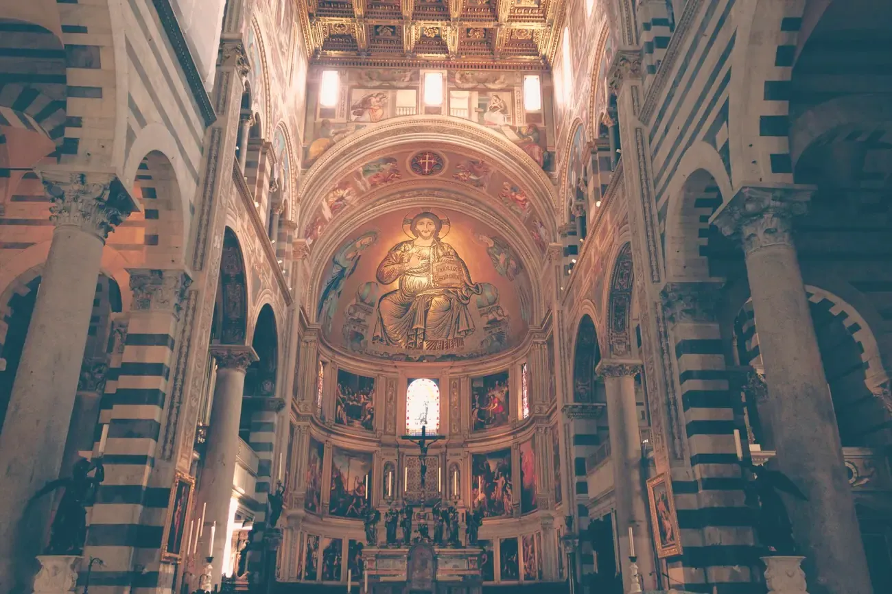 The striped nave of Pisa Cathedral leading to the golden apse mosaic of Christ