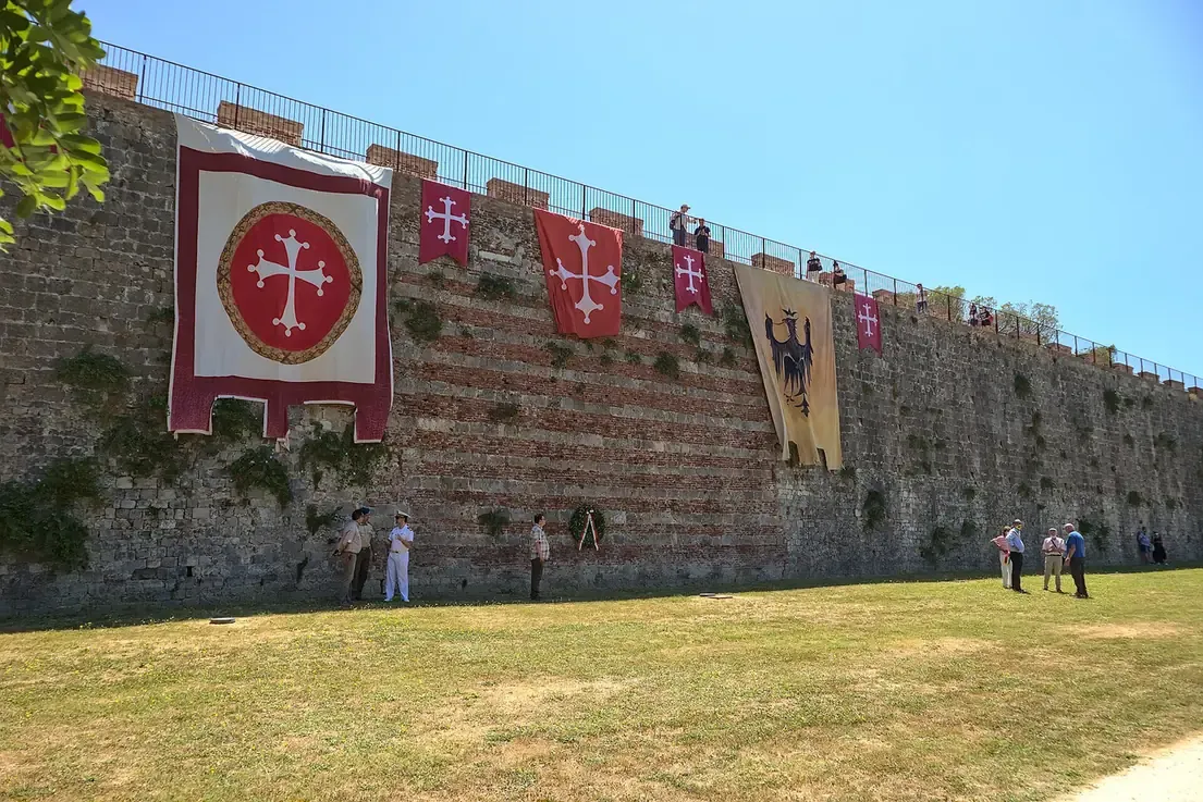 Historic banners hanging on the medieval walls of Pisa at the Parco delle Concette