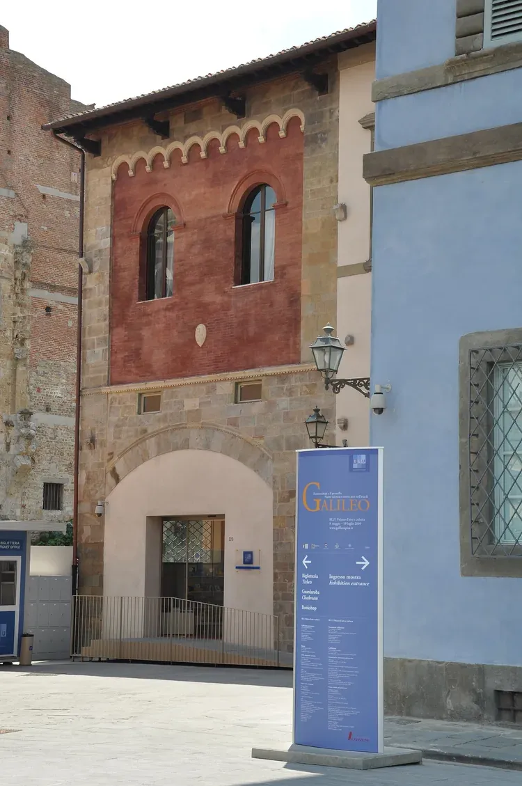 The blue facade of Palazzo Blu beside a medieval brick tower house in Pisa