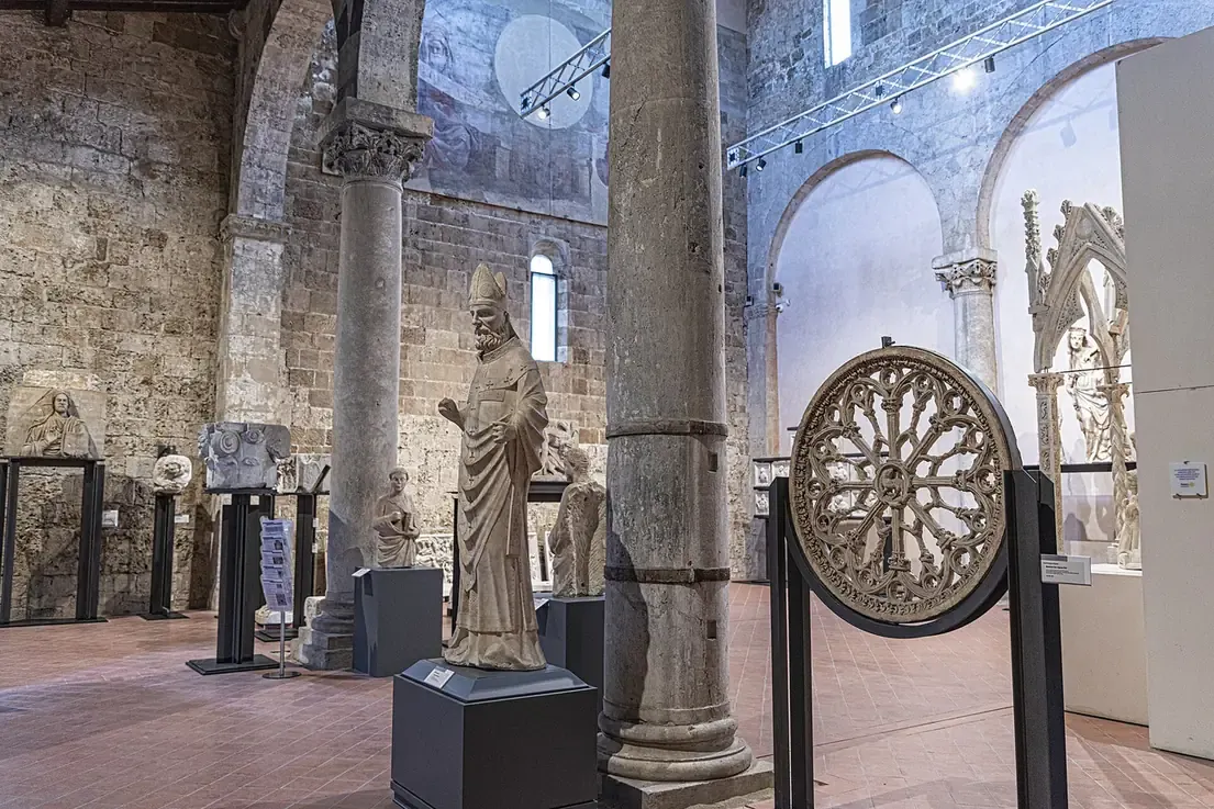 Medieval sculptures and a rose window in a vaulted hall of the San Matteo museum in Pisa