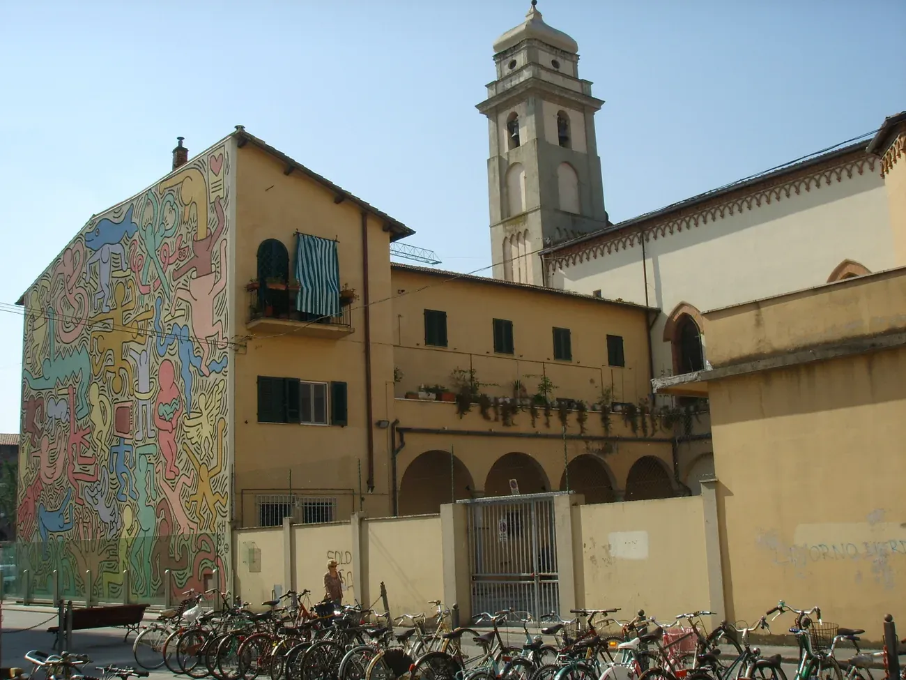The side of the Sant'Antonio Abate church and convent in Pisa with its bell tower and the Tuttomondo wall at an angle