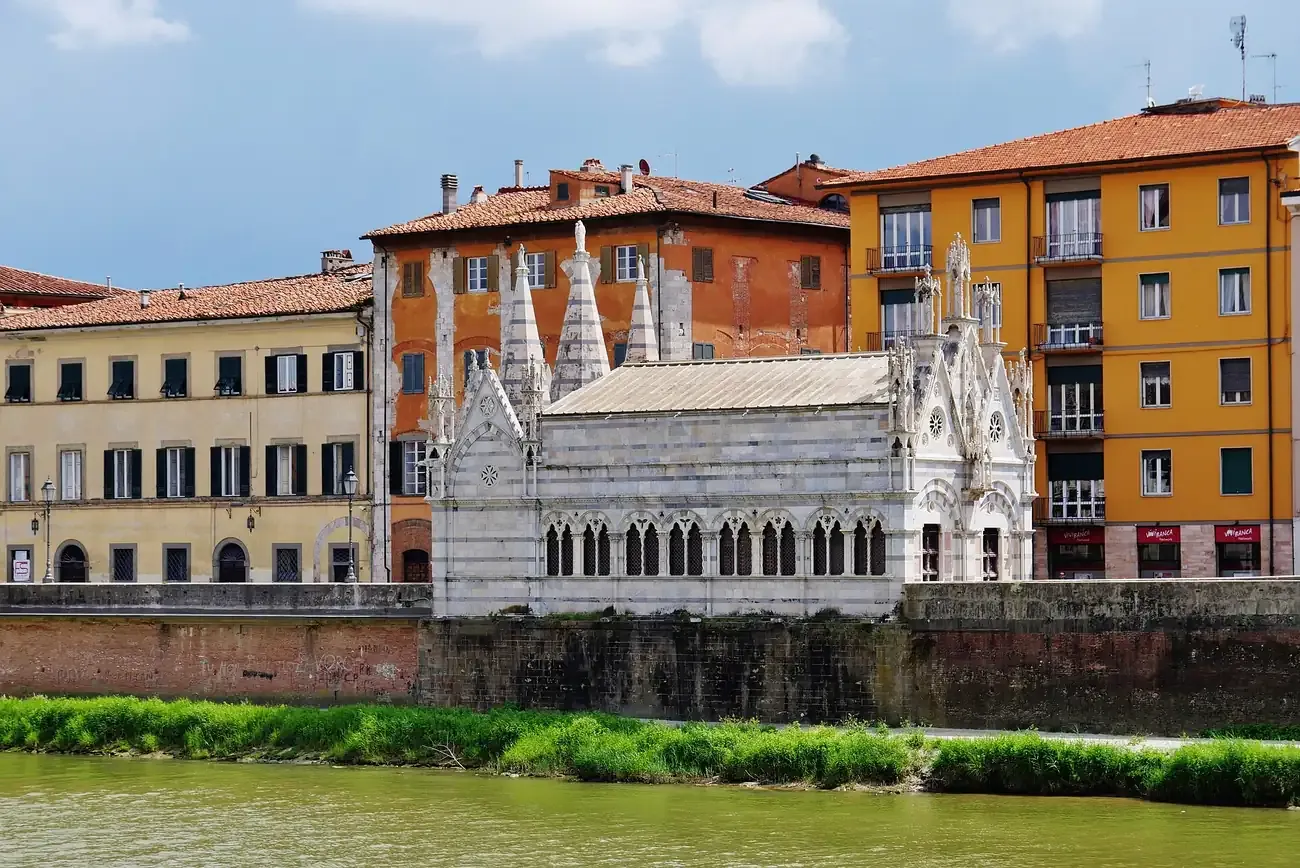 Santa Maria della Spina seen across the Arno with colourful riverside houses in Pisa