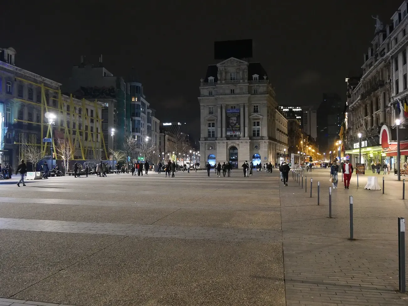 The Place De Brouckère in Brussels at night, with a domed corner building at the end of the square