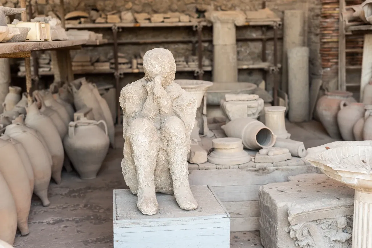 Plaster cast of a seated victim among amphorae in the storerooms of Pompeii
