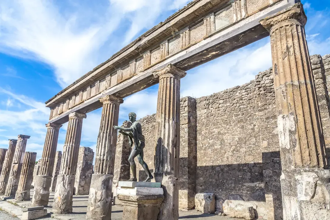 Columns of the Temple of Apollo with its bronze archer statue in the ruins of Pompeii