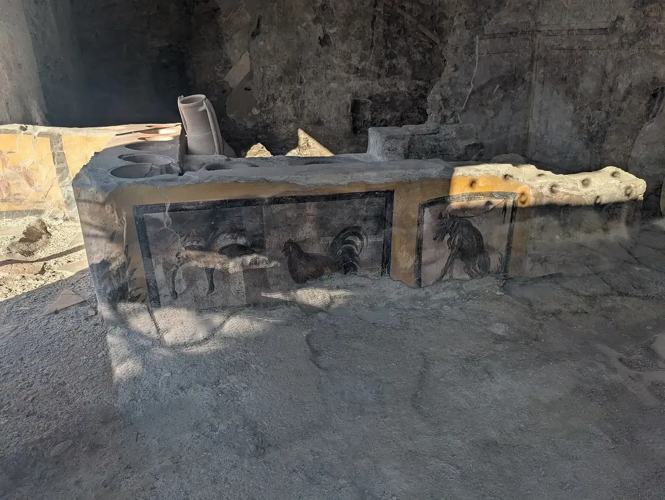 The masonry counter of the Thermopolium of Regio V in Pompeii, painted with a rooster and a dog on a leash