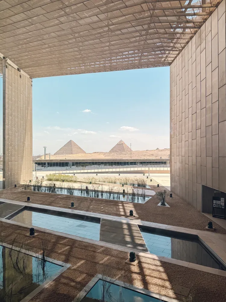 The Pyramids of Giza framed by modern architecture and a reflecting pool, Cairo