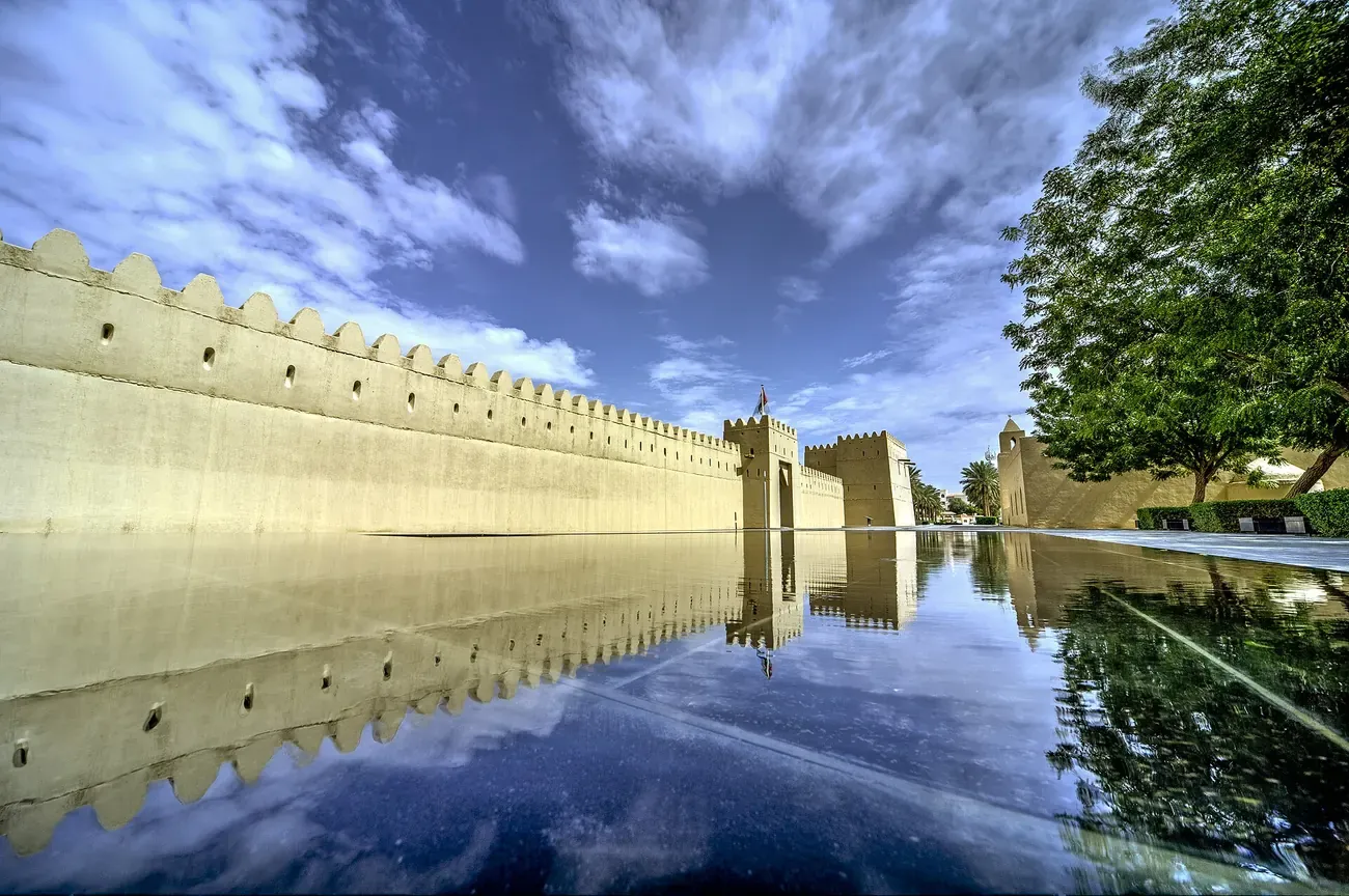 The mudbrick walls of Qasr Al Muwaiji reflected in water at Al Ain