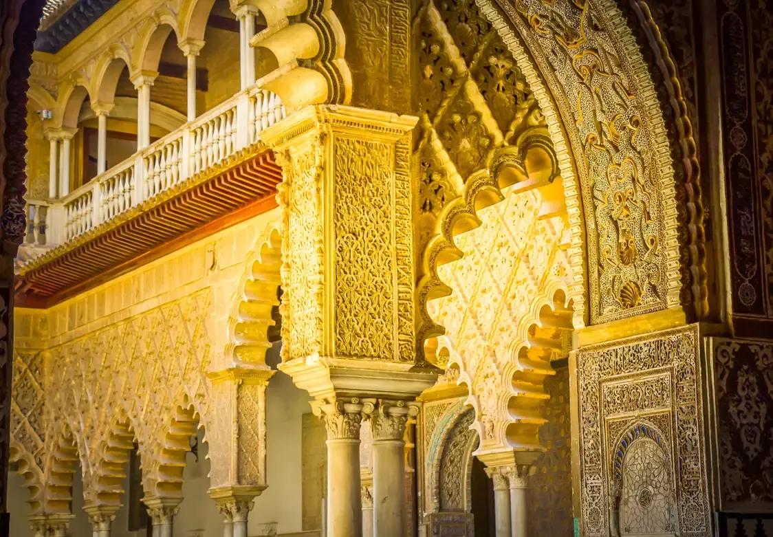 Ornately carved arches lit with golden light at the Real Alcazar, Seville